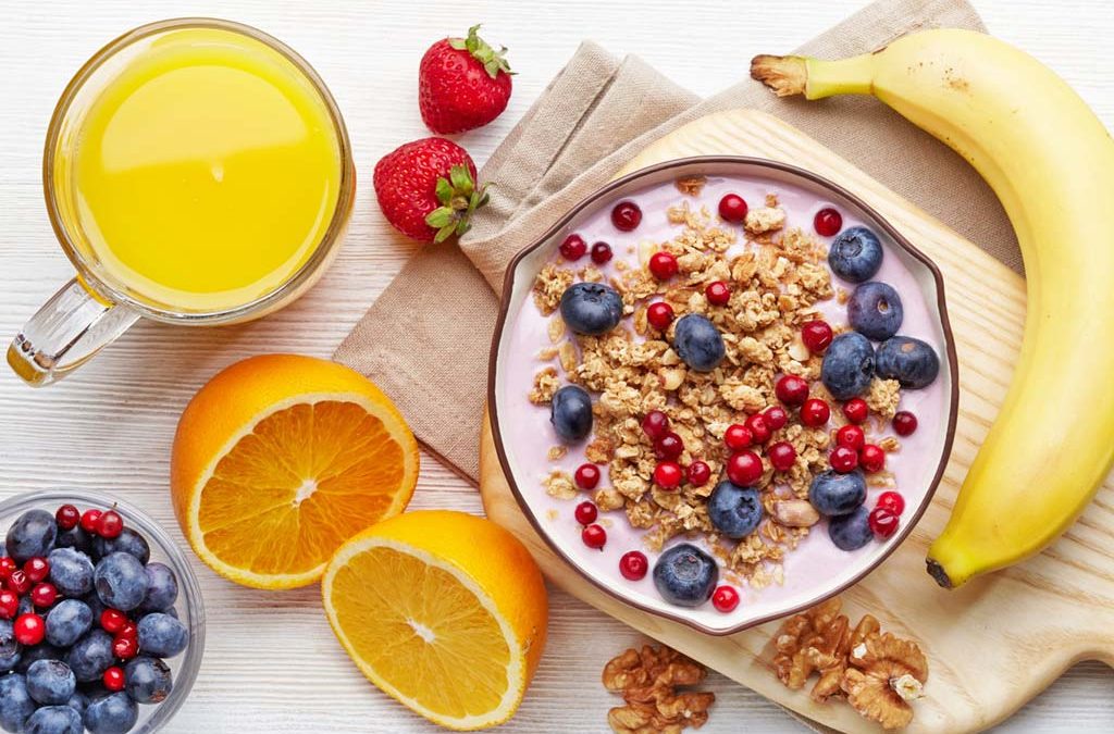 a bowl of fruit sitting on top of a wooden table